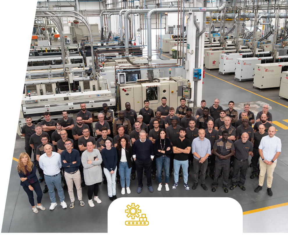 Group photo of the Eredi Baitelli team inside the factory, with production lines and machines in the background.