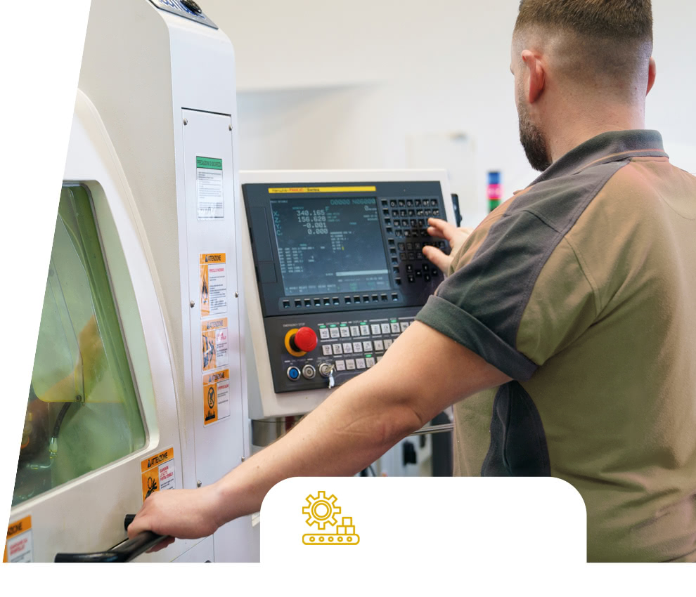 Eredi Baitelli operator using the CNC machine control panel next to the machine enclosure.