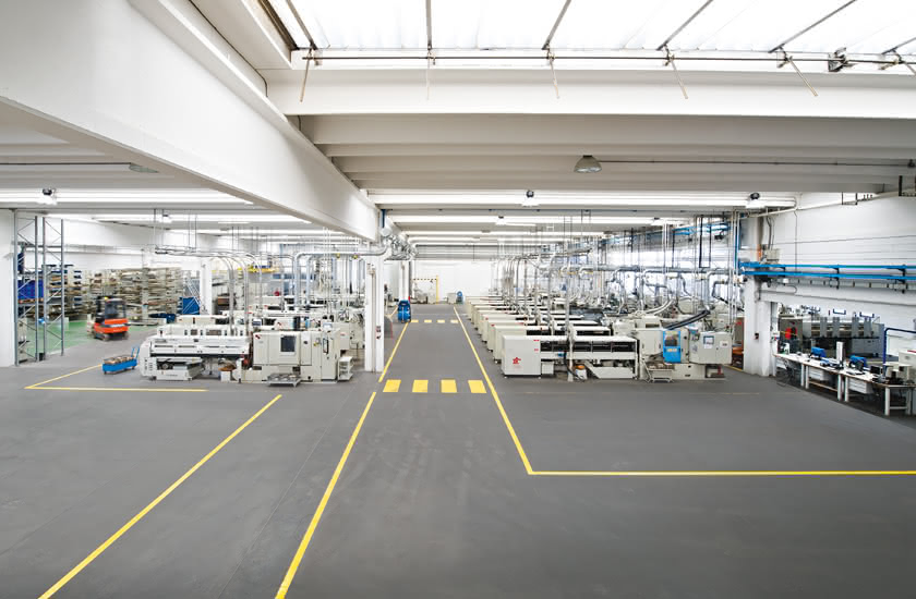 Inside the Eredi Baitelli factory, opened in 1990 in Zocco di Erbusco, with automatic lathes and clearly marked safety lanes.