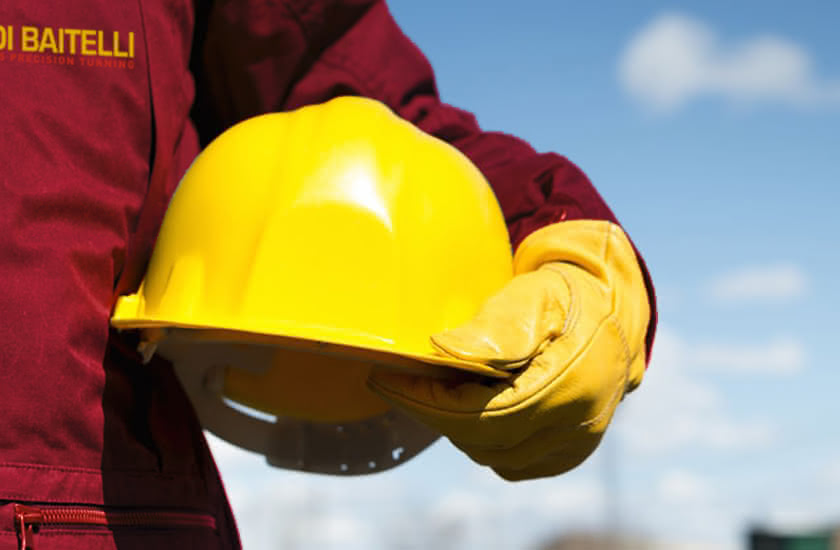 Eredi Baitelli worker wearing a yellow helmet and work gloves, symbolizing commitment to safety.