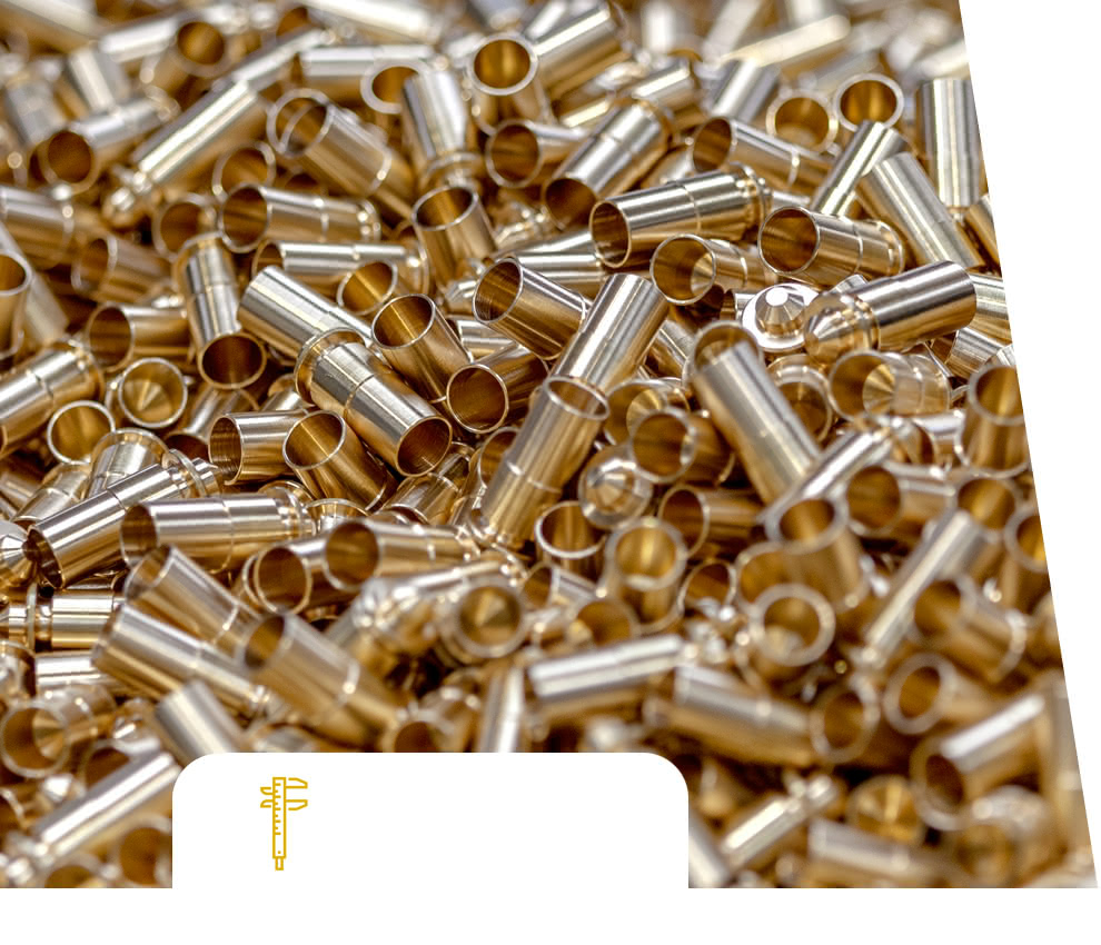 Stacked brass-turned bushings and pins, ready for dimensional and surface checks in the metrology room of the turning department.